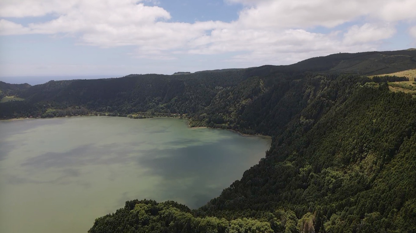 Aerial view of a crater lake surrounded by forested slopes
