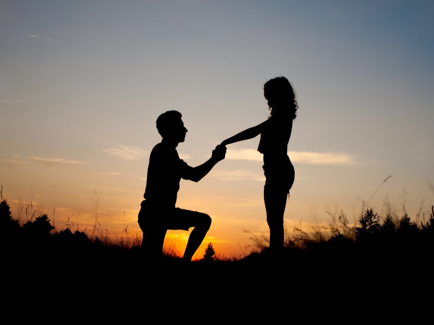Silhouetted couple at sunset during a proposal